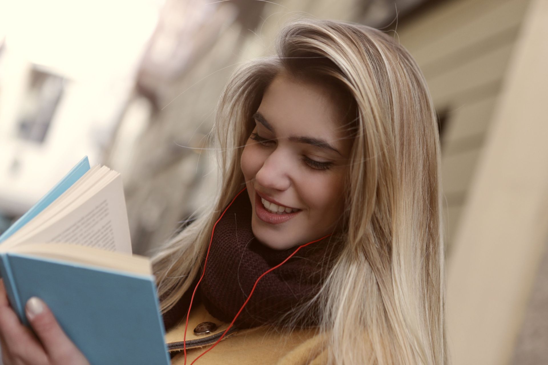 Shallow Focus Photo of Woman Smiling While Reading a Book